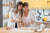 Two women in the kitchen holding an egg while taking online cooking courses.